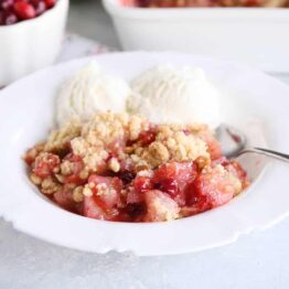 Bowl of cranberry pear crumble with vanilla ice cream.