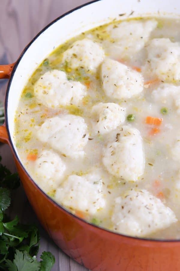 Orange cast iron pot filled with chicken dumpling soup.