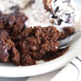 Spoonful of decadent hot fudge pudding cake on white plate.