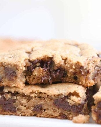 Bite taken out of peanut butter chocolate chip bar on white platter.