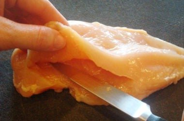 Slicing Chicken raw chicken breast being cut in half