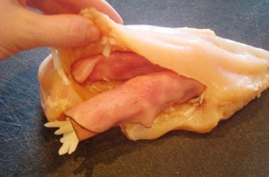 Stuffing 2 raw chicken breast cut open and getting stuffed with ham and cheese