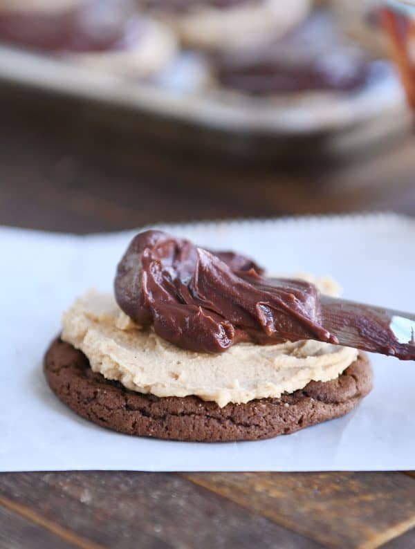 Spreading chocolate ganache on chocolate peanut butter buckeye cookie.