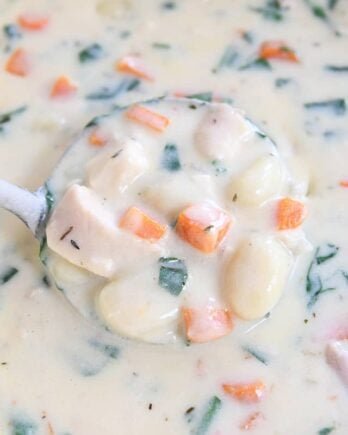 ladle scooping out portion of creamy chicken gnocchi soup in blue pot