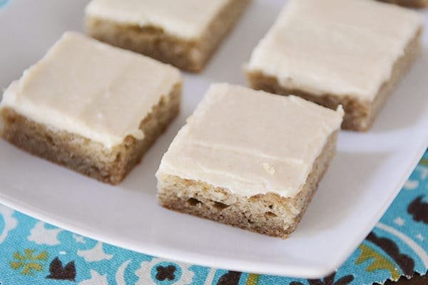 A white platter with iced banana bars.