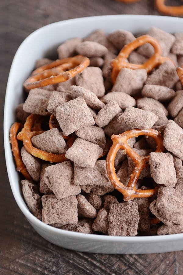 Top view of a white bowl of chocolate muddy buddies and pretzels.