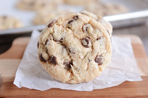 A chocolate chip cookie tipped on it's side on a piece of parchment.